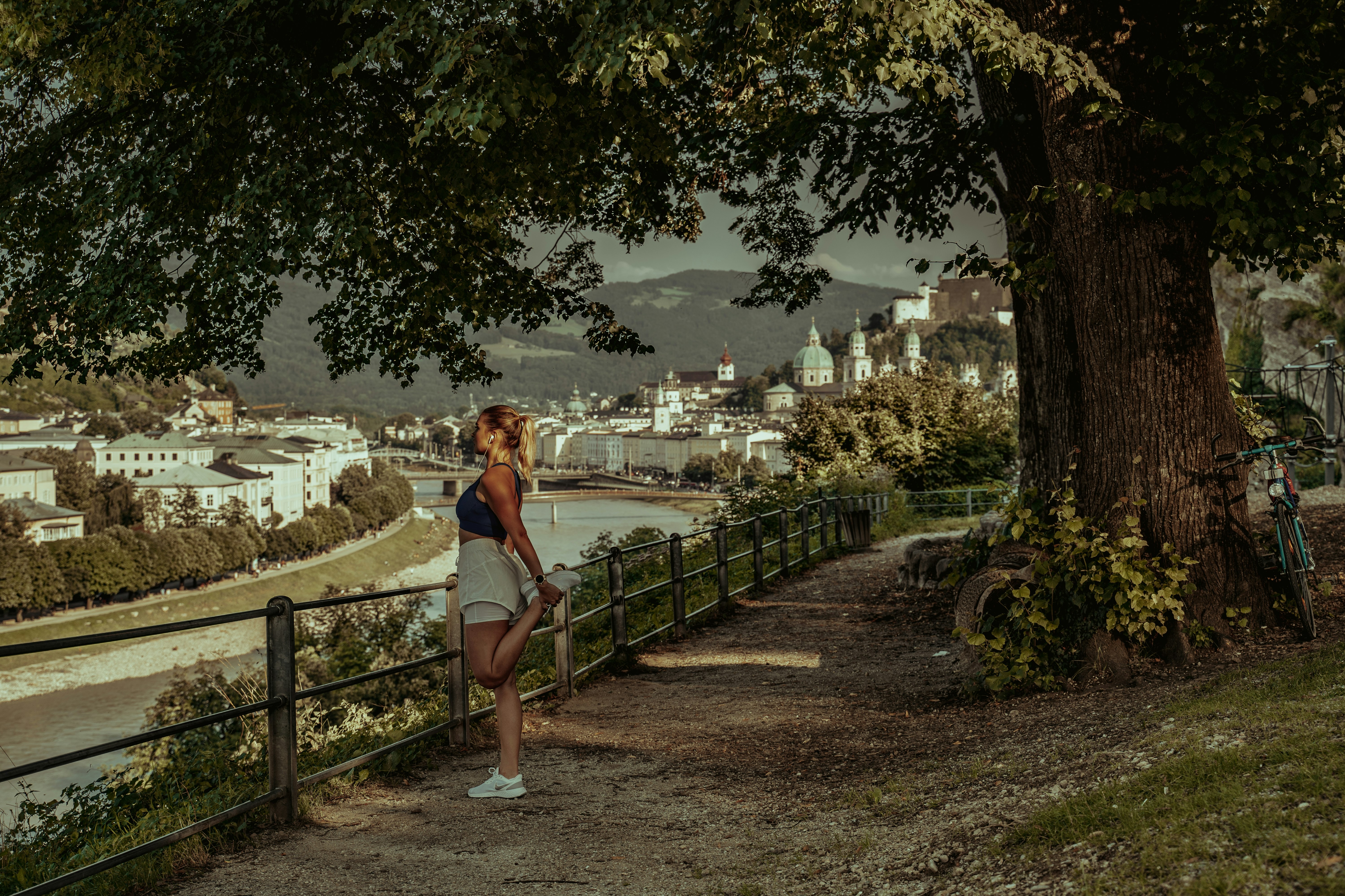 woman in white tank top and blue denim shorts standing on brown wooden bridge during daytime